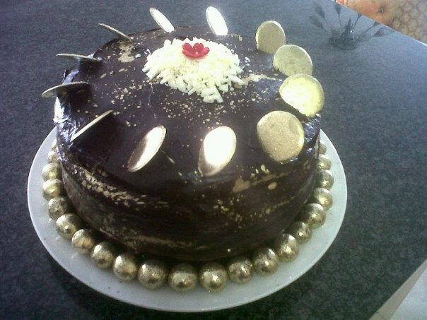 golden death by choc cake - 3 layer moist choc cake with amarula cream filling, choc ganache topping and golden whisper balls, golden white choc disks, white choc shavings and golden splatters.  R350